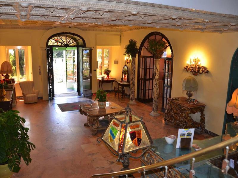 Inviting hotel lobby area with colorful lamps, antique furniture, and open entrance door.