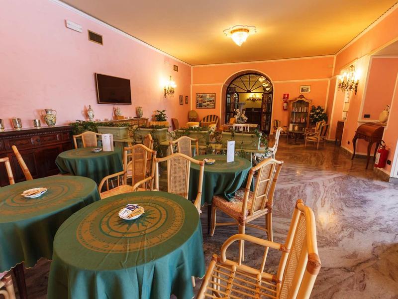 Cozy breakfast room with green tablecloths, wooden chairs, and warm lighting.