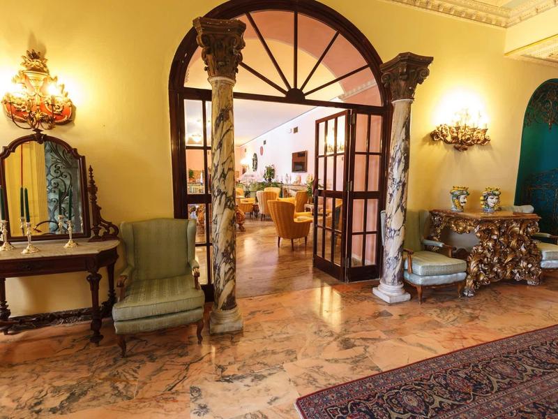 Elegant hotel lobby with antique furniture, columns, and warm lighting.