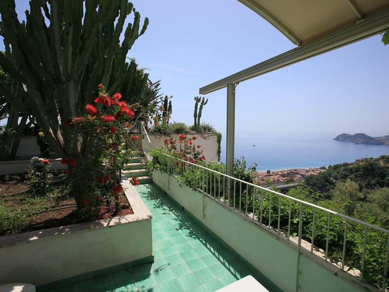 Balkon met groene planten en uitzicht op zee op een zonnige dag.