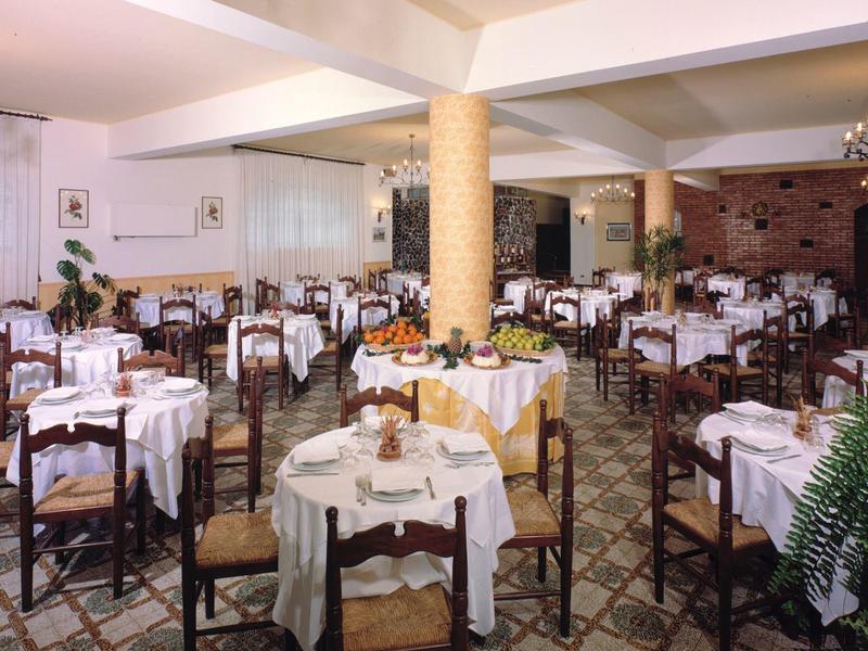 Großer Speisesaal mit vielen runden Tischen, weiß gedeckt und dunklen Holzstühlen in hellen Räumen.