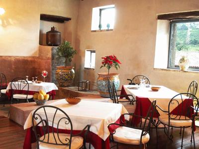 Gemütlicher Restaurantbereich mit runden Tischen, weißen Tischdecken, Stühlen und Pflanzen.