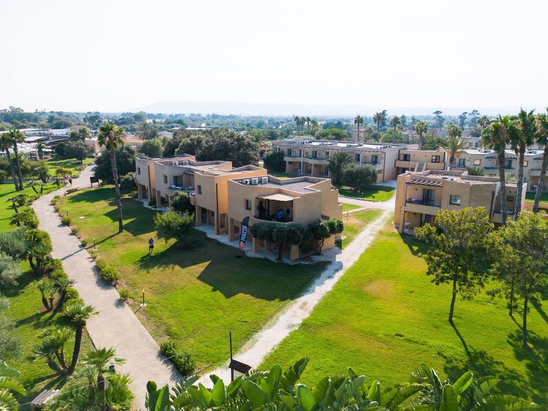 Letecký pohled na moderní prázdninové vily s zelenými trávníky a cestičkami v obytném komplexu.