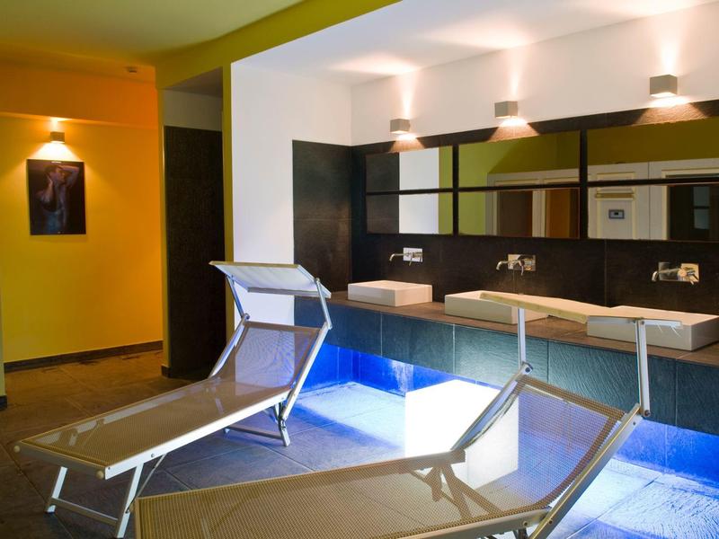 Moderní hotelový salon s modrým osvětlením, lehátky a umyvadly se zrcadly.