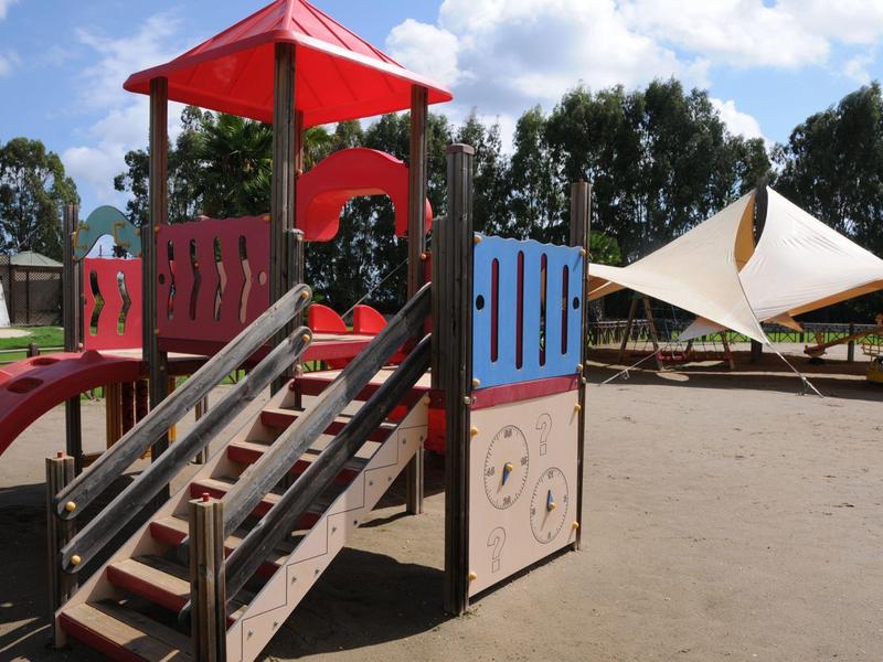 Barevné dětské hřiště s skluzavkou a prolézačkou za slunečného počasí.