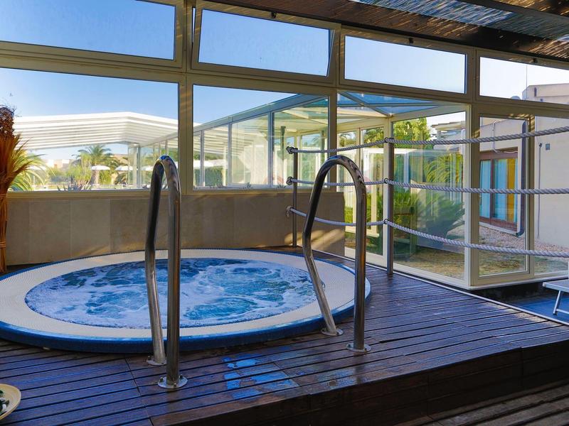 Vírivka na zastřešené terase se skleněnými okny a výhledem ven.