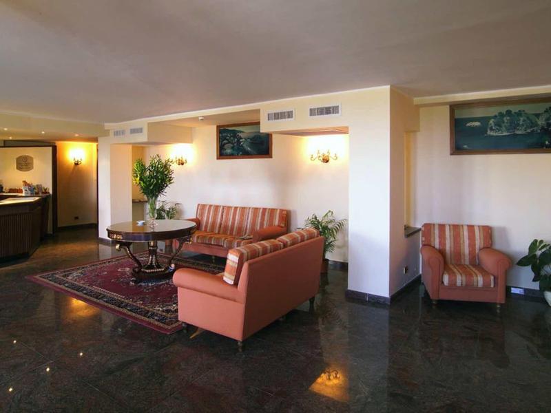 Heller Warteraum mit rotbraunen Sesseln, dunklem Boden und Empfangstresen in der Ecke.