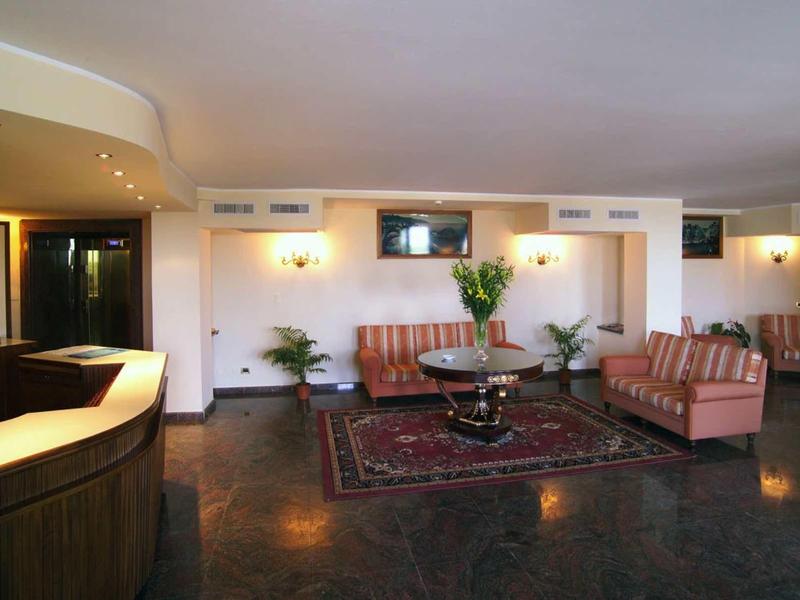 Modern eingerichtetes Wohnzimmer mit zwei gestreiften Sofas, Teppich und runder Glas-Tisch.