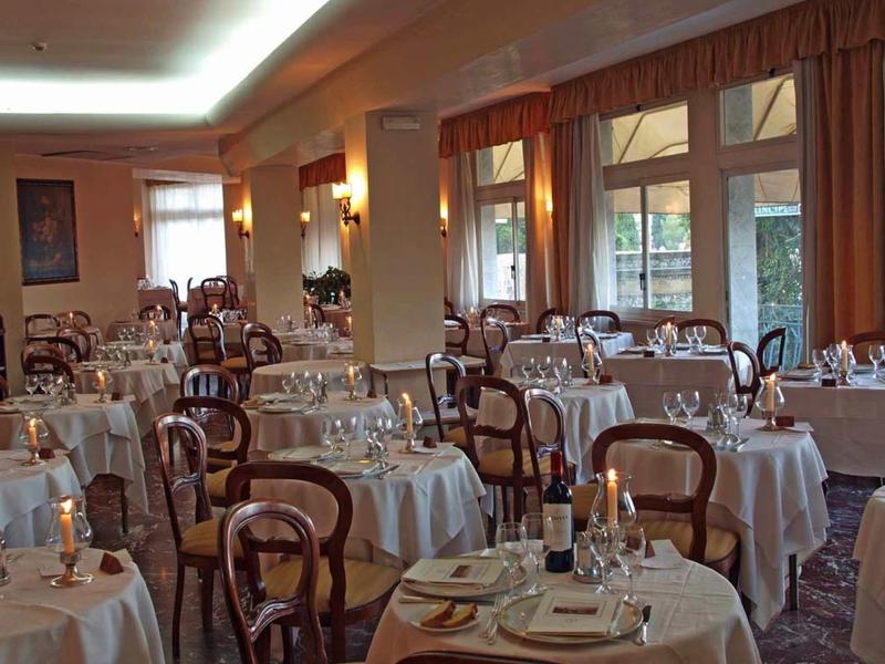 Restaurant mit runden Tischen, weiß gedeckte Tafeln und Holzstühlen in hellen, gemütlichen Raum.