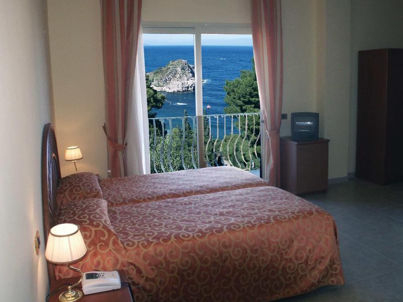 Zimmer mit zwei Einzelbetten, braunen Bettdecken, Nachtlampen und Meerblick durch großes Fenster.