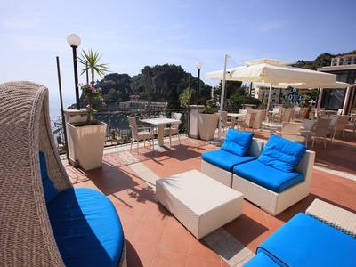 Moderne Außensitzgruppe mit blau gepolsterten Möbeln auf Terrasse mit Meerblick.