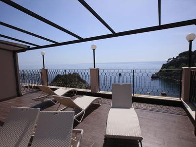 Terrazza soleggiata con lettini e vista mare al crepuscolo.