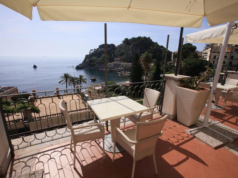 Terrazza con tavoli e sedie con vista sul mare e ombrelloni in una giornata di sole