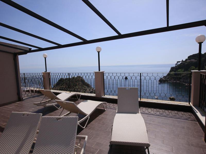 Terrazza soleggiata con lettini e vista mare al crepuscolo.