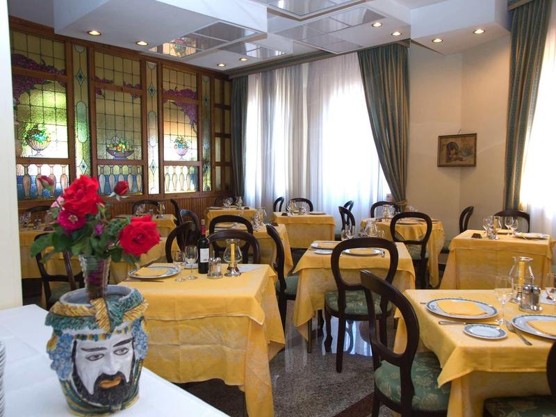 Pohodlná jídelna se žlutými ubrusy a květinovou dekorací.