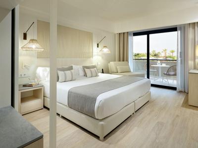 Helles Hotelzimmer mit Doppelbett, Balkon und moderner Einrichtung.