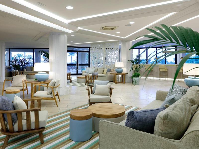 Spacious hotel lobby with modern seating, large windows, and indoor plants creating a relaxing atmosphere.