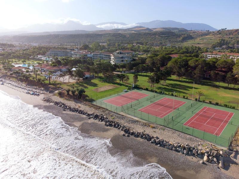 Coastal resort with tennis courts, green lawns, and buildings near the beach and ocean