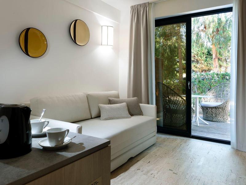 Cozy hotel room with a sofa, coffee set, and sliding glass door opening to a garden patio.