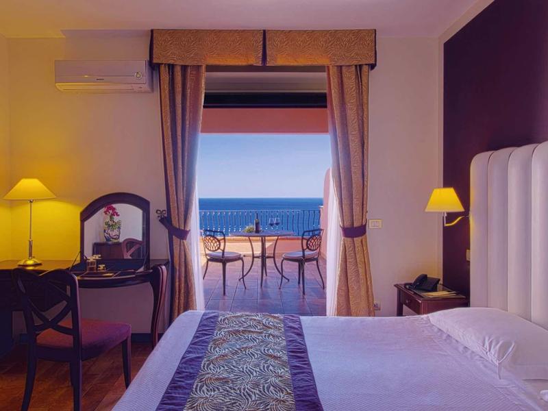 Hotelkamer met groot bed en balkon met uitzicht op zee