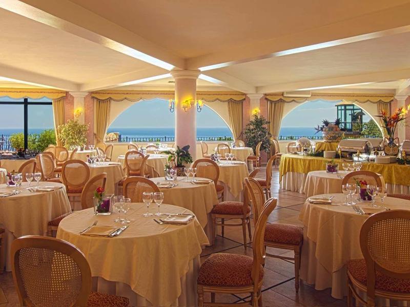 Elegant restaurant met ronde tafels, comfortabele stoelen en uitzicht op zee.