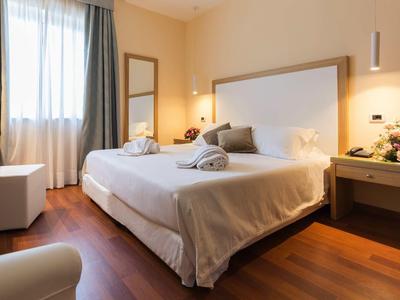 Modern hotelkamer met tweepersoonsbed, houten vloer en natuurlijk licht via raam.