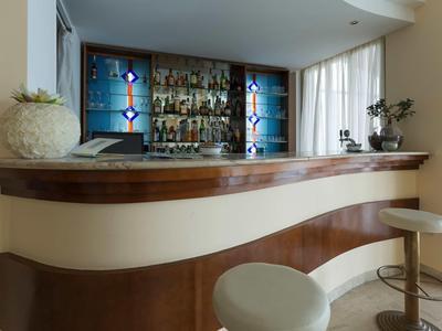 Moderne hotelbar met gebogen houten toonbank en krukken voor verlichte planken.