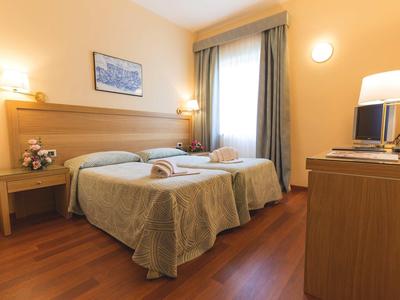 Hotelkamer met twee eenpersoonsbedden, houten meubels en warm licht.