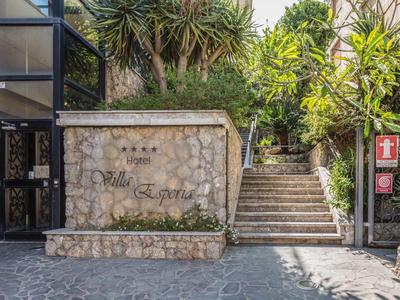 Ingang met stenen bord en trap omgeven door groene planten bij Villa Esperia.