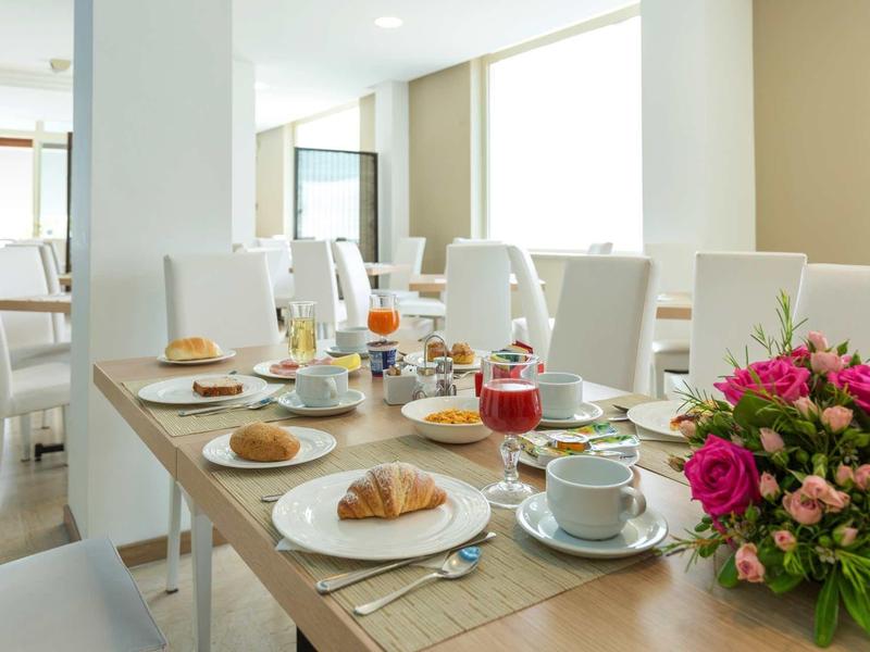 Lichte eetkamer met gedekte ontbijttafel en verse bloemen op tafel.