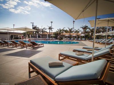 Strefa basenowa z leżakami i parasolami pod niebieskim niebem