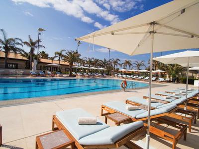 Espace piscine avec chaises longues et parasols par une journée ensoleillée