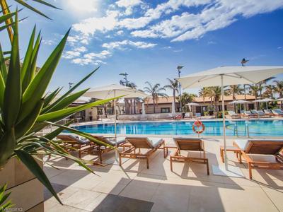 Zapraszający basen z leżakami i parasolami pod niebieskim niebem