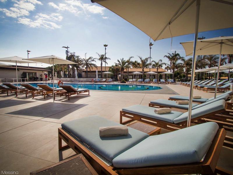 Strefa basenowa z leżakami i parasolami pod niebieskim niebem