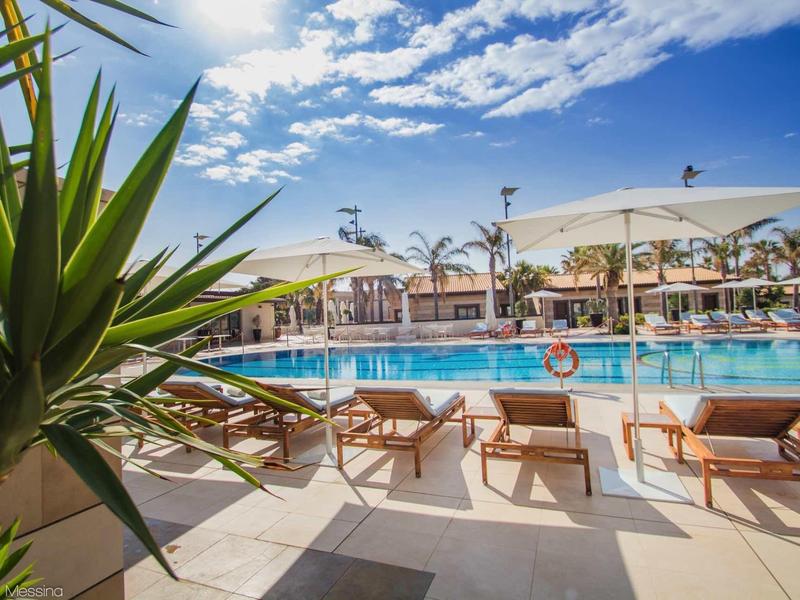 Zapraszający basen z leżakami i parasolami pod niebieskim niebem