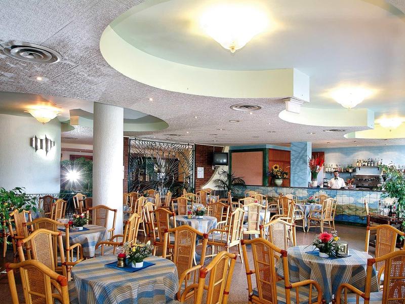 Zona ristorante dell'hotel luminosa e accogliente con mobili in legno e tavoli apparecchiati.