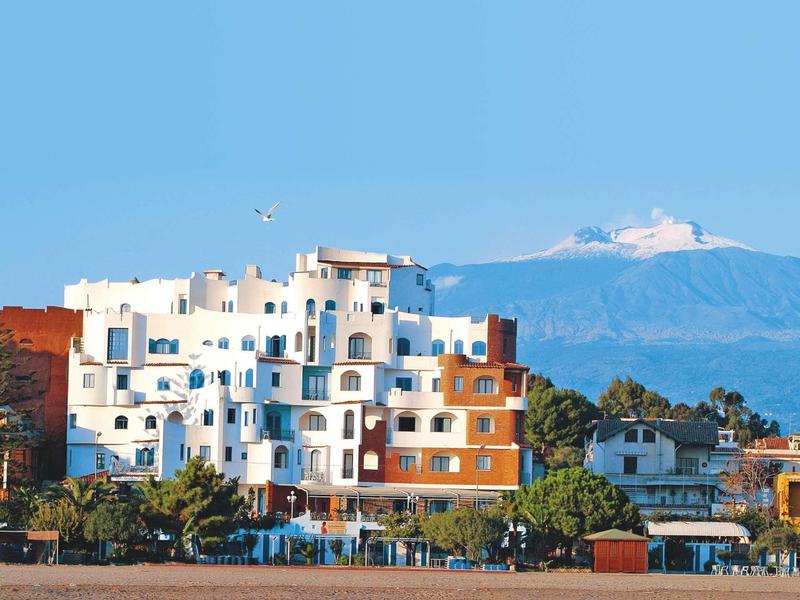 Edificio dell'hotel sulla spiaggia con montagna innevata e cielo blu sullo sfondo