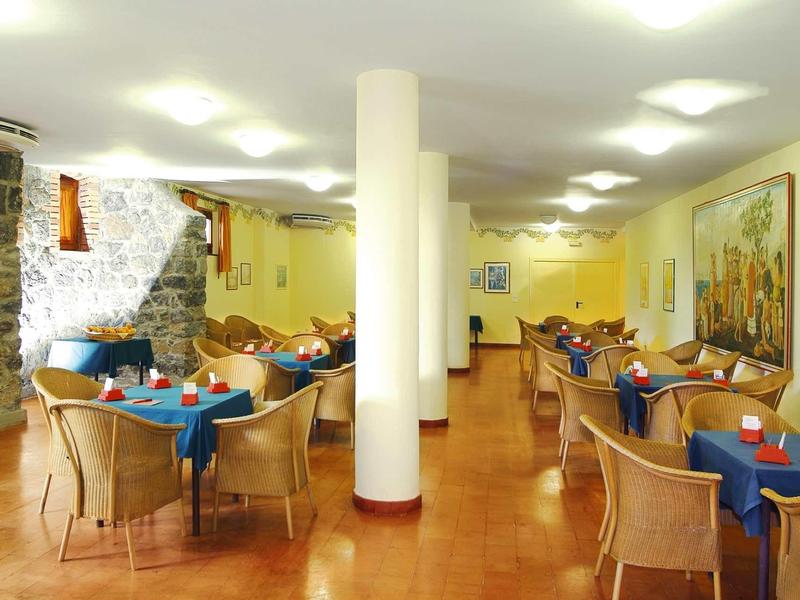 Sala da pranzo luminosa con tovaglie colorate e sedie in rattan