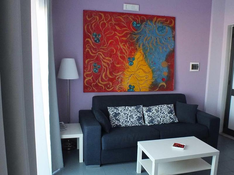 Moderne woonkamer met donkerblauwe bank, kleurrijk kunstwerk en witte salontafel