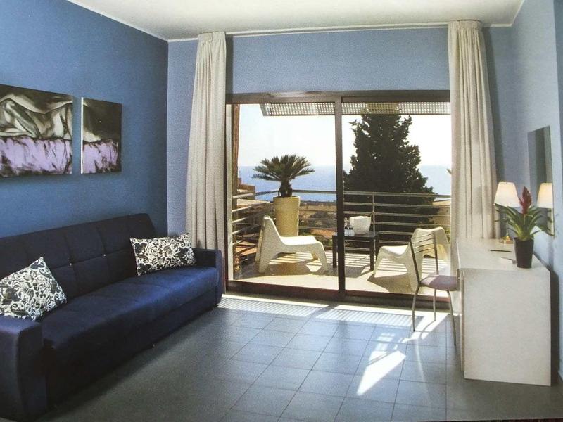 Modern ingerichte woonkamer met uitzicht op zee, bank en balkon met stoelen