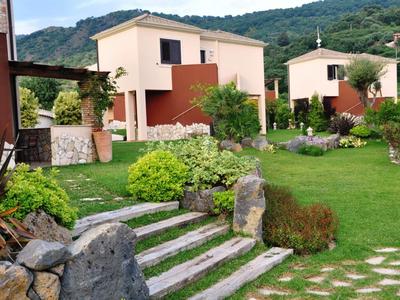 Due case vacanze moderne con giardini e vista sulle montagne in una giornata di sole.