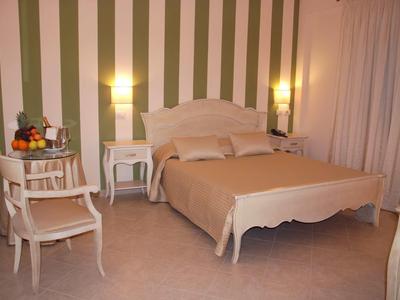 Una camera luminosa con letto matrimoniale, due comodini, sedie e un cesto di frutta.