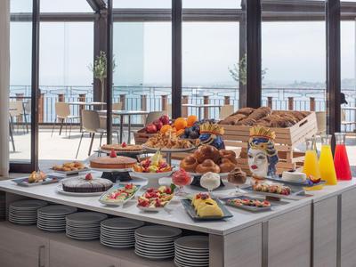 Buffet per colazione con pasticceria, frutta, succhi e pani su un tavolo con vista.
