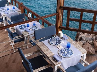 Ristorante in terrazza con tovagliati blu e bianchi con vista sul mare.