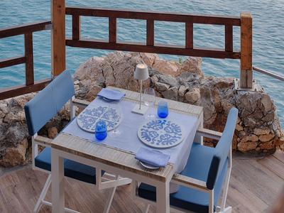 Un tavolo apparecchiato con stoviglie blu su una terrazza con vista mare.