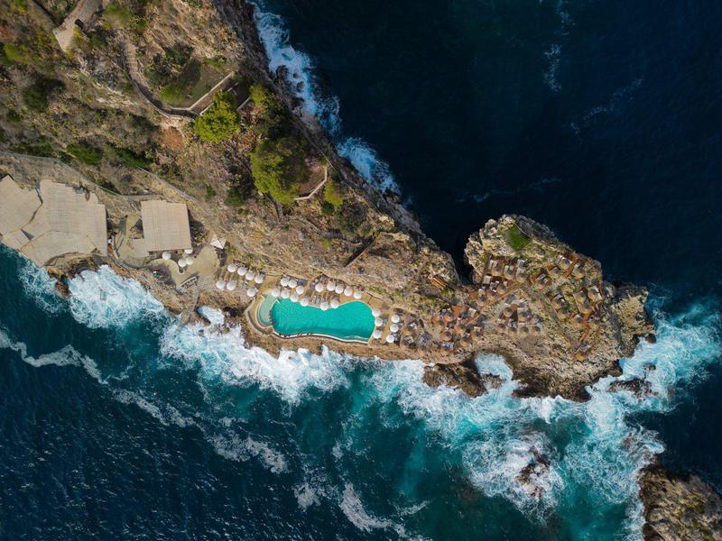 Luchtfoto van een natuurlijk rotszwembad aan zee met golven en omgeven door rotsen
