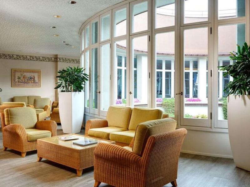 Lichte hotel lounge met grote ramen, comfortabele fauteuils en planten