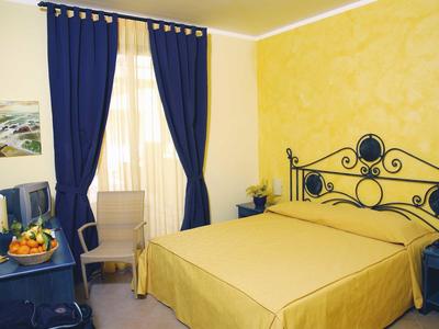 Cozy hotel room with yellow bedding, blue wrought iron bed, and blue curtains.