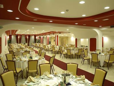 Large, festively set dining room with yellow chairs and red accents on walls and ceiling.