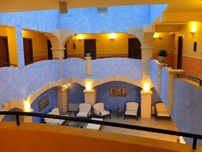 Hotel courtyard with two floors, white walls, and seating areas on the lower level.